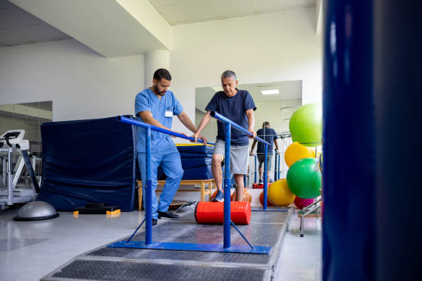 Latin American man doing physical therapy and walking on bars while pushing a roller with his leg