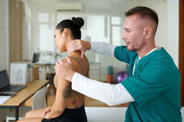 Sports massage specialist massaging neck and shoulder of female patient