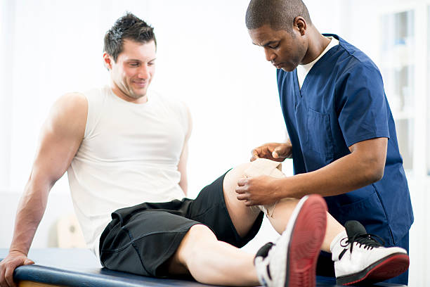 A nurse, or physiotherapist, applying pressure to a sports injury in a physical therapy clinic.