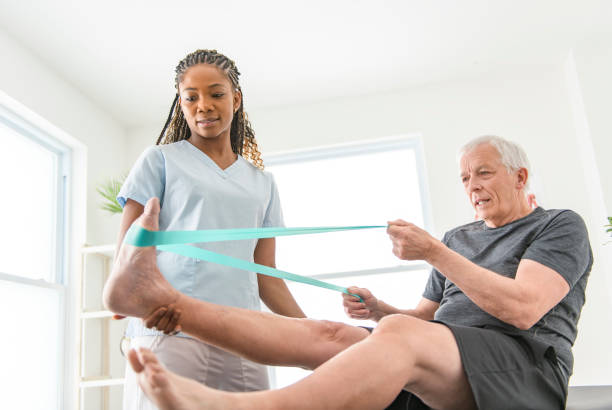 A black Physiotherapist helping senior man with in clinic. Elderly man undergoing physiotherapy treatment for injury