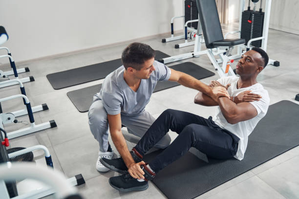 Physiotherapist applying pressure to crossed arms and foot of patient during resisted isometric testing