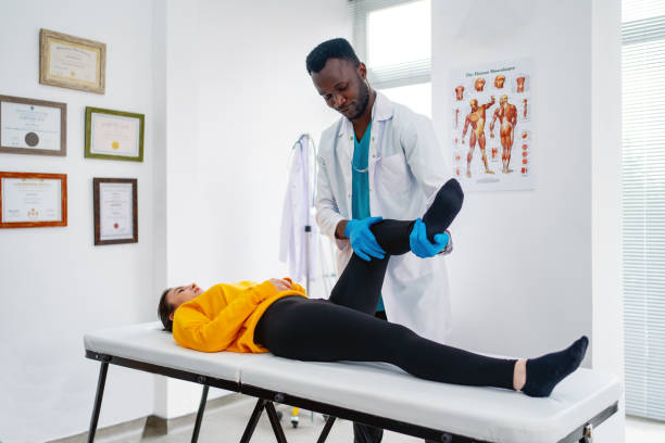 Therapist treating injured knee of athlete female patient in clinic